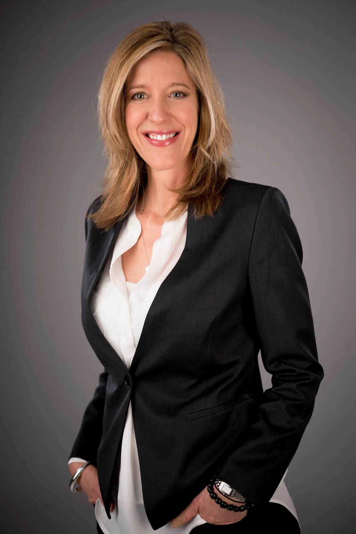 Corporate headshot of a businesswoman in a black blazer on a dark background