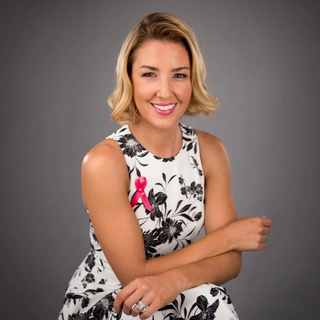 A smiling woman in a black and white floral dress, seated