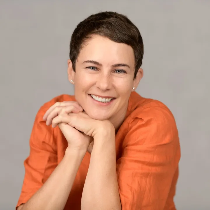 The same woman laughing, her hands folded beneath her chin