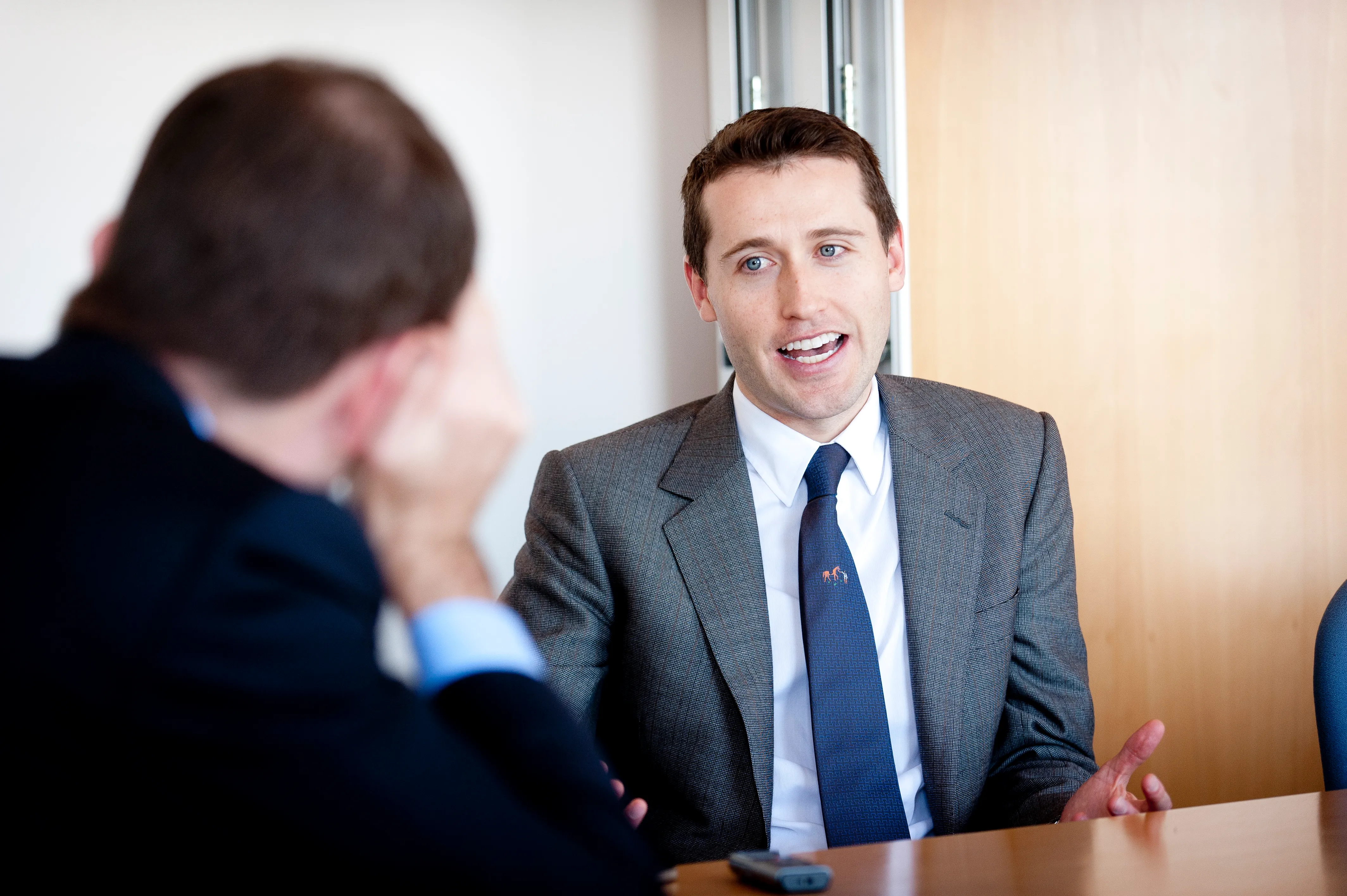 A businessman photographed mid conversation across a meeting table