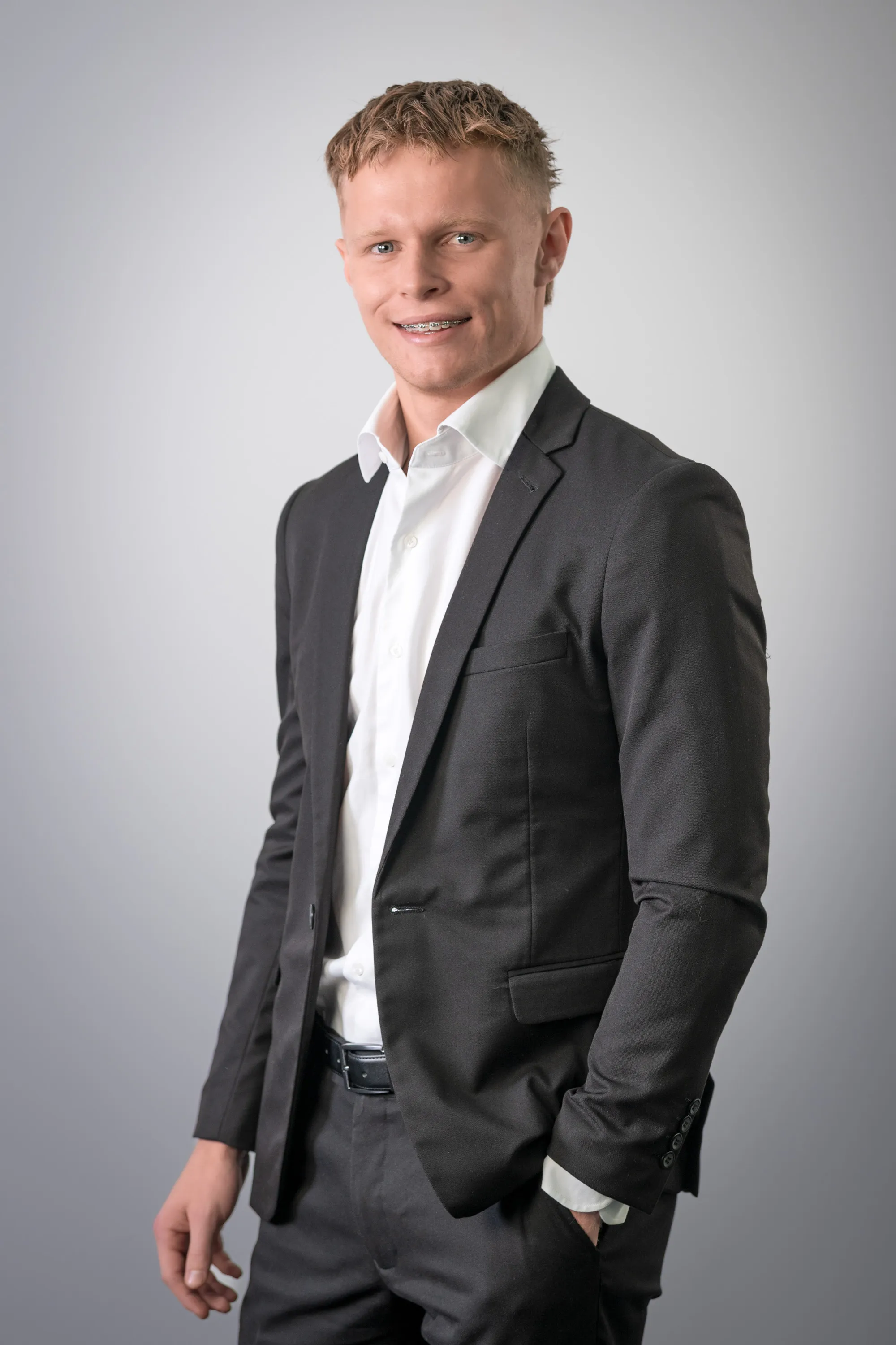 Professional headshot of a young man in a charcoal suit